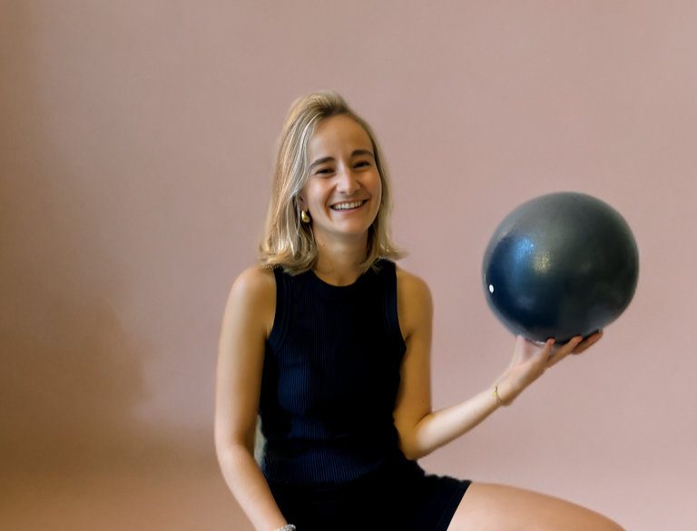 Portrait d’Eléonore Boonen, souriante, tenant un ballon de Pilates